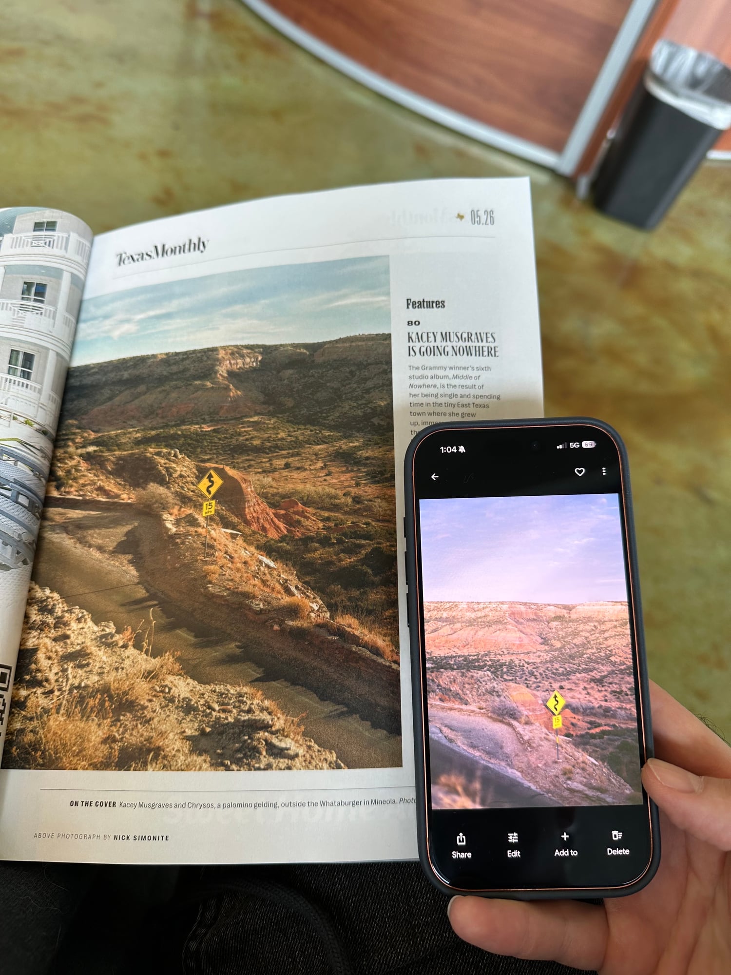 An open Texas Monthly magazine showing a canyon photograph, with a phone held beside it displaying a nearly identical photo of the same canyon